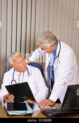 Two senior doctors talking in hospital office to each other Stock Photo