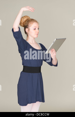 Young blond female teenager in ballet dress holding a tablet pc Stock Photo