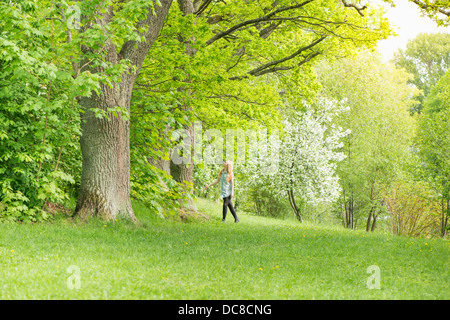 Nature scene with one young attractive woman standing by a tree in a park Stock Photo