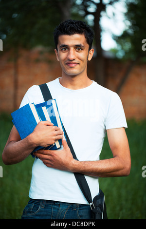 Arab male student with books outdoors looking very happy Stock Photo