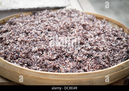 Cooked steam black rice in big wooden plate dish with shallow depth of field Stock Photo