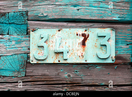 Rusted house number on grunge green wooden wall Stock Photo