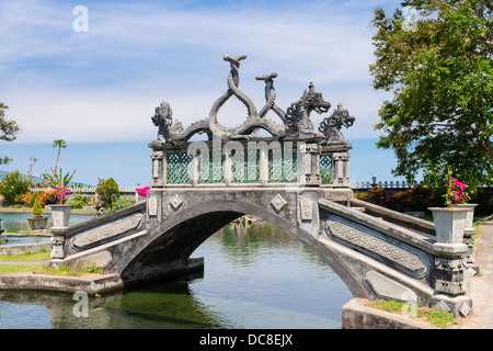 Stone balinese style arch bridge in a park with gragon images, Tirtaganga, Bali Stock Photo
