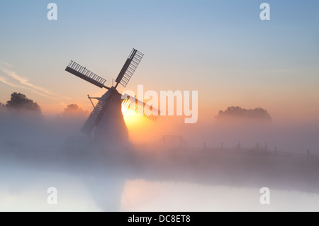 Dutch windmill in dense fog at sunrise Stock Photo