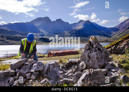 Rock outcrop and Bla Bheinn and Beinn Na Caillich Cuillin mountains; Geologist at Loch Slapin Marble quarry at Ben Suardal, Isle of Skye, Scotland, UK Stock Photo