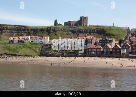 People enjoying the beach at Whitby, the harbor houses and the abbey are in the background. Stock Photo