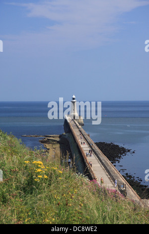 People walking along the North Pier towards the lighthouse at Tynemouth at the mouth of the River Tyne, Northumberland, England Stock Photo
