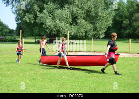 Children carrying kayak back to boat shed on River Thames, Pangbourne, Berkshire, England. United Kingdom Stock Photo
