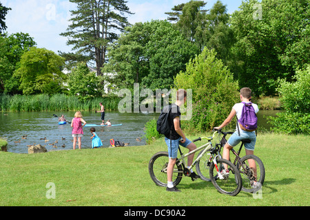 Boys on bicycles and children kayaking on River Thames, Pangbourne, Berkshire, England. United Kingdom Stock Photo