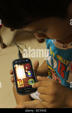 Indian 4 year old toddler playing fruit ninja on a smart phone Stock Photo