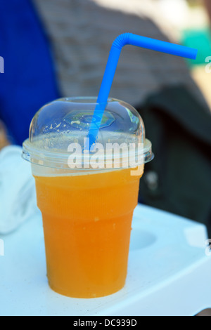 Cold freshly squeezed orange juice on a white plastic beach table in Greece Stock Photo