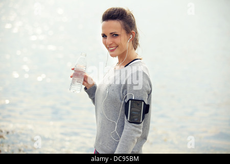 Happy female runner smiling while holding a bottled water Stock Photo