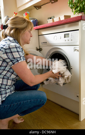 Caucasian woman loading washing machine at home, taken in Bristol, England, uk Stock Photo