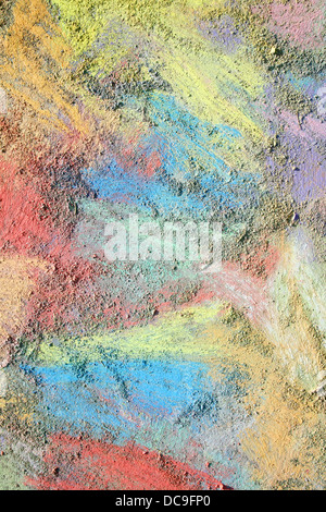 an abstract background of bright, rainbow colored sidewalk chalk smeared and drawn on the pavement Stock Photo