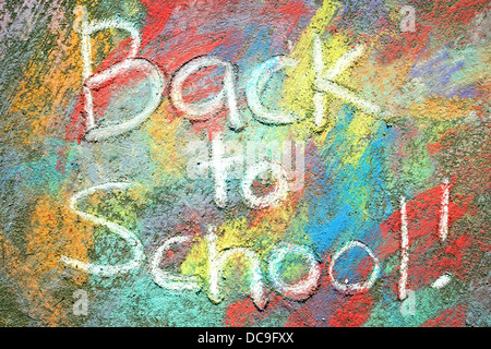 The words Back to School are written in white sidewalk chalk, on a background of rainbow tye-dye colors drawn on the pavement. Stock Photo
