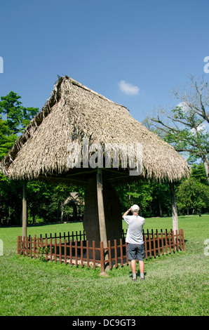 Guatemala, Quirigua Mayan Ruins Archaeological Park. Grand Plaza with carved stone stele protected by small thatched huts. Stock Photo