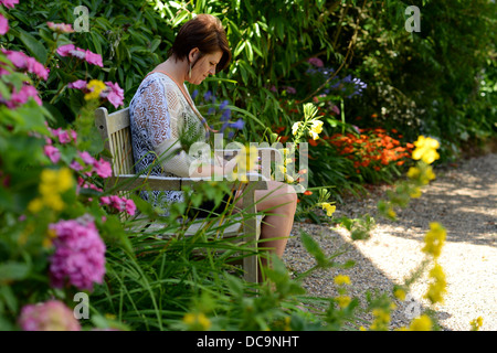 Woman alone sat on park bench Stock Photo