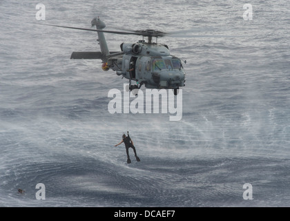 A search and rescue swimmer assigned to the Scorpions of Helicopter Anti-Submarine Squadron (HSL) 49 prepares to rescue a simulated man overboard during a helicopter cast off and recovery exercise with the Arleigh Burke-class guided-missile destroyer USS Stock Photo
