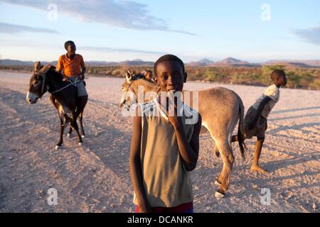 Children with their donkeys are pictured on the street to Palmwag in the Damaraland near Twyvelfontein in Namibia, 8 December 2010. Photo: Tom Schulze Stock Photo