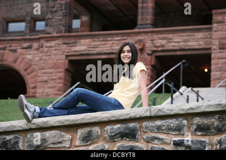 Teen girl sitting on rock ledge Stock Photo