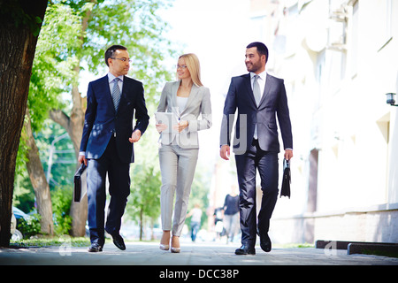 Image of elegant colleagues walking and discussing business matters on the move Stock Photo