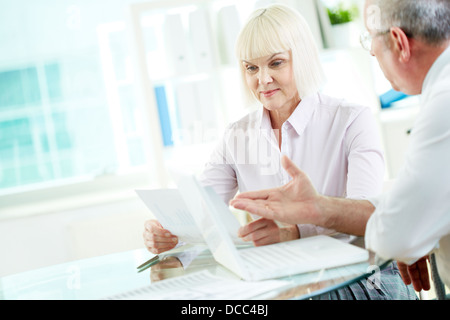 Two mature business partners discussing papers at meeting Stock Photo