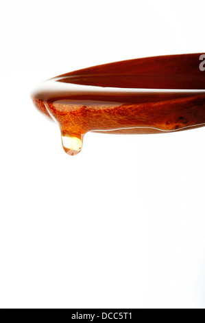 Honey dripping from a wooden spoon Stock Photo