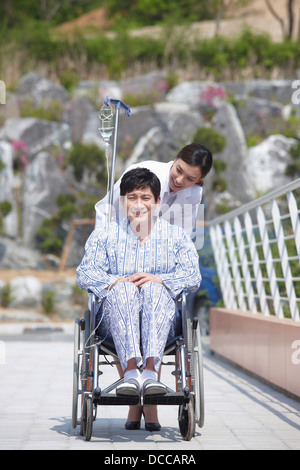 a female doctor behind a patient with a wheel chair Stock Photo