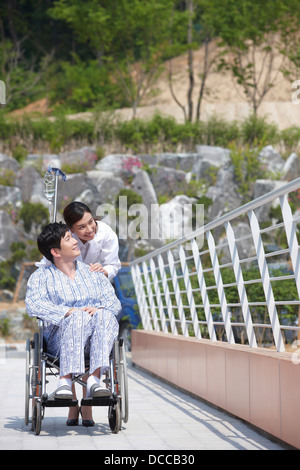 a female doctor behind a patient with a wheel chair Stock Photo