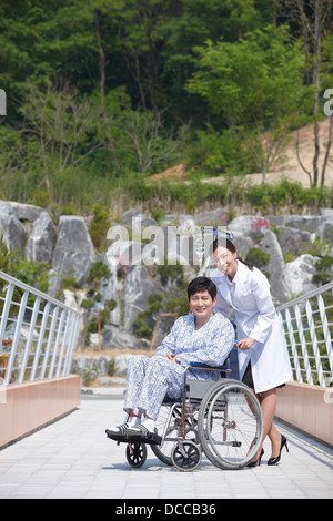 a female doctor behind a patient with a wheel chair Stock Photo