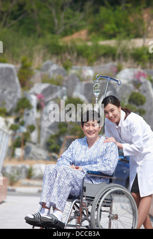 a female doctor behind a patient with a wheel chair Stock Photo