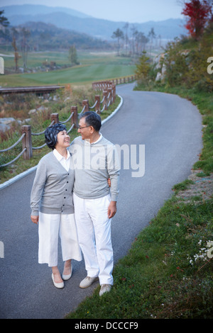 middle aged couple along an empty street surrounded by nature Stock Photo