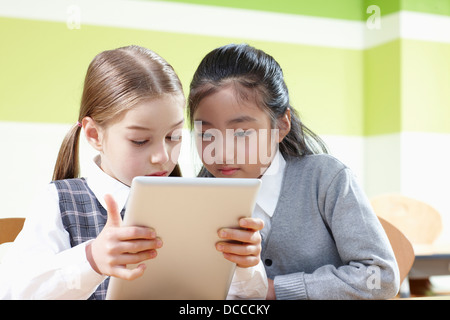 students sharing a tablet PC in a classroom Stock Photo