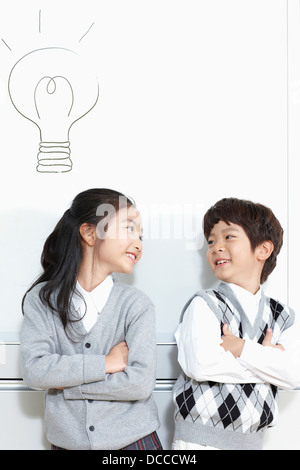 girl and boy student standing with arms crossed smiling at each other Stock Photo