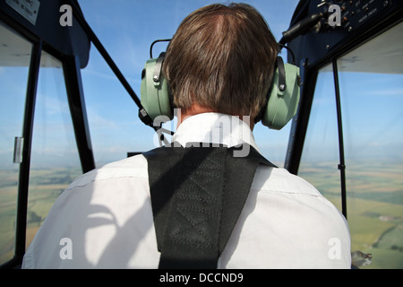 the back of a pilot of a Piper PA18 Supercub light aircraft in flight Stock Photo