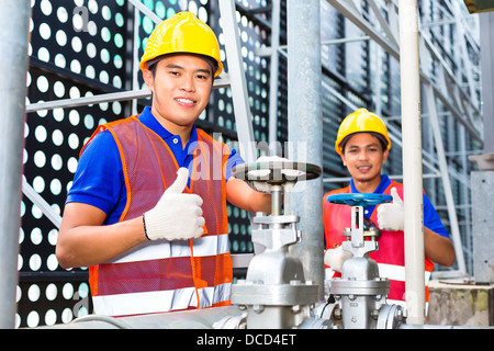 Two technicians or engineers working on a valve on building technical equipment or industrial site Stock Photo