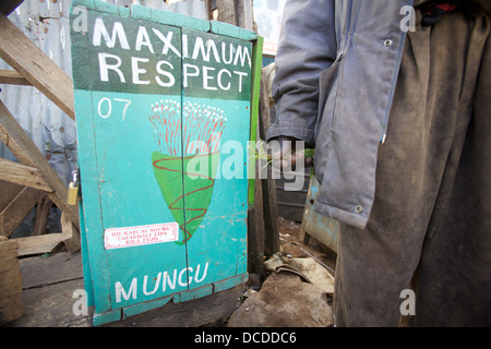 Hand holding khat next to a painted sign advertising khat bundles and emblazoned with ' Maximum Respect' Meru Region, Kenya Stock Photo