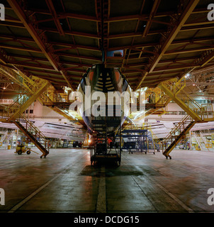 A Boeing 747 is surrounded by gantries during late night work by engineering staff perform maintenance checks in the British Airways engineering hangar on the far side of London's Heathrow airport. Stock Photo