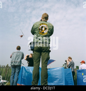 An airshow aviation enthusiast adorned with badges enjoy aerobatic activity above their heads at Biggin Hill, Kent, England. Stock Photo
