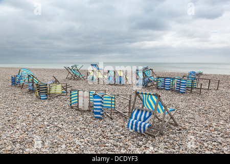 Deck Chairs blown over in high winds on pebbly beach in Beer, Devon. Stock Photo