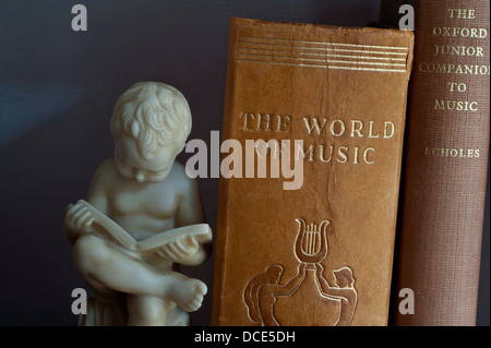MUSIC STUDY STUDYING BOOKS HOBBY INFORMATION Carved bookend statue of boy reading alongside classical music books in library Stock Photo