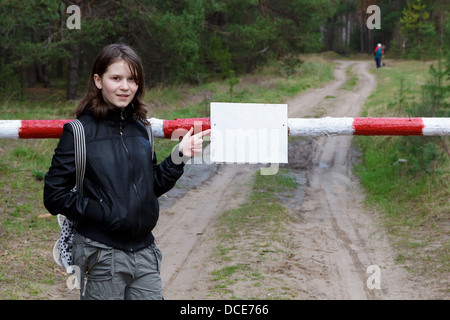 teen girl points to sign on the barrier Stock Photo