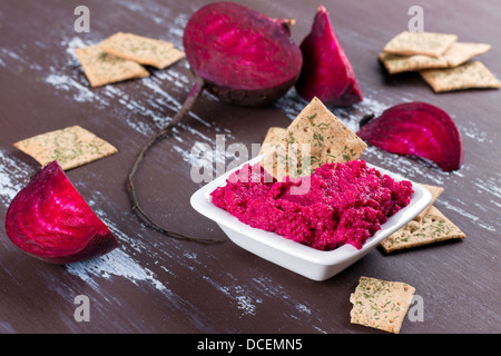 Portion of beetroot hummus with raw beetroot and crackers on background Stock Photo