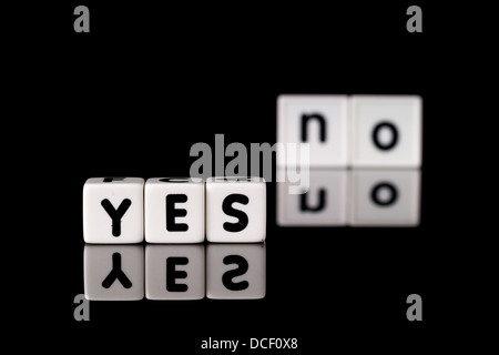 Yes spelled in dice letters in foreground with the word no out of focus in background. Isolated on black background. Stock Photo