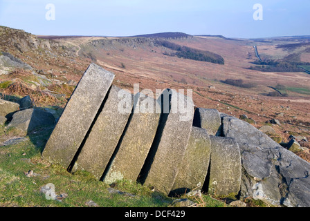 Millstones lie abandoned in situ at the old quarry site at Stanage Edge, Peak District, UK Stock Photo