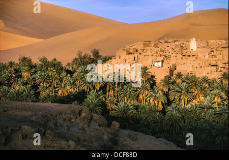 Sand dunes of the Grand Erg Occidental tower over the oaisis township of Taghit in North west Algeria. Stock Photo