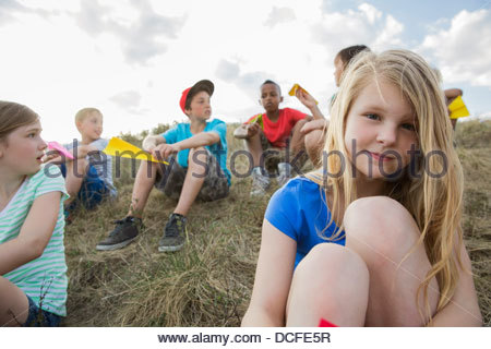 Portrait of cute girl sitting with friends outdoors