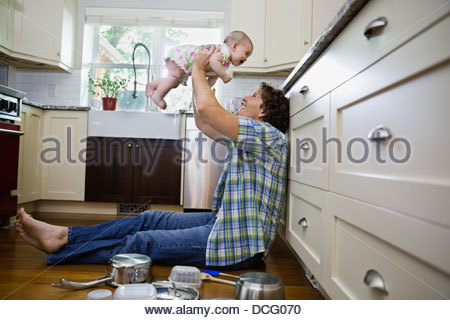 Profile shot of father playing with baby girl in kitchen