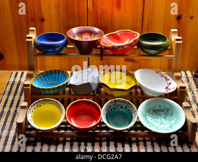 Colorful glazed bowls displayed on wooden stand Stock Photo