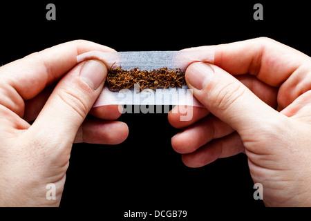 Hands Rolling a Cigarette Paper with Tobacco Stock Photo